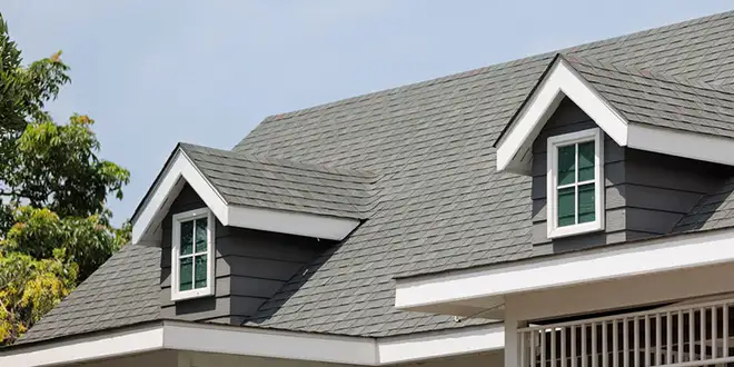 Roofer inspecting shingles and flashing during a roof inspection
