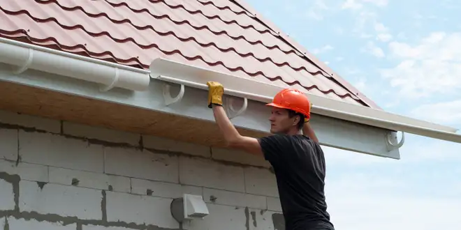 Technician repairing a sagging section of eavestrough on a residential roofline