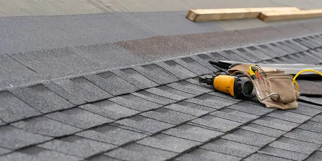 Roofer checking asphalt shingles during a maintenance visit